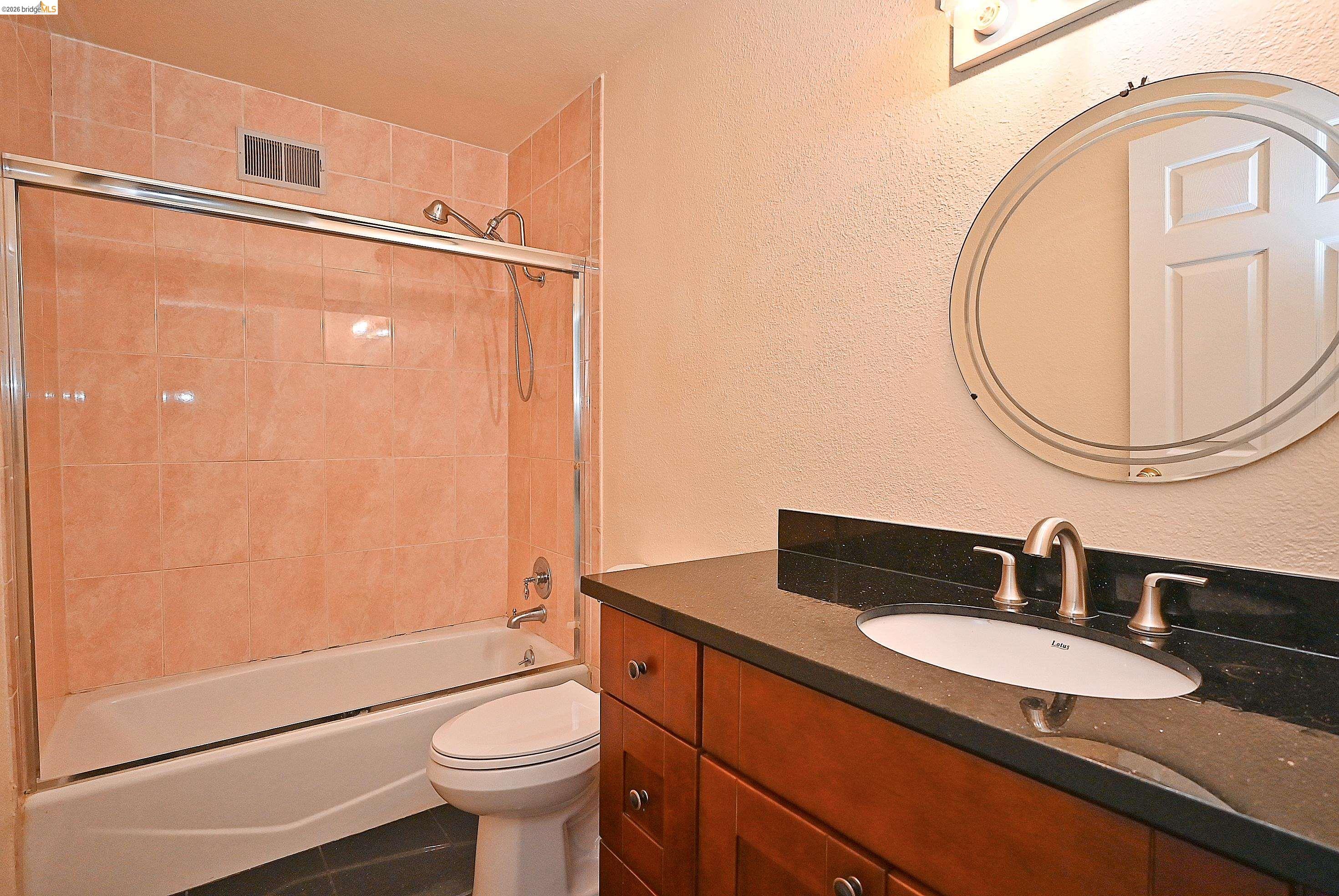 159 Coleridge Drive Vallejo, CA 94591 - Photo 28 of 33 Full bath with a textured wall, vanity, bathing tub / shower combination, and dark tile patterned floors