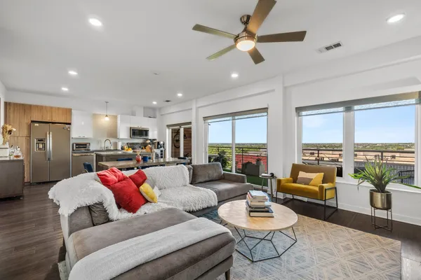 a living room with furniture kitchen view and a large window