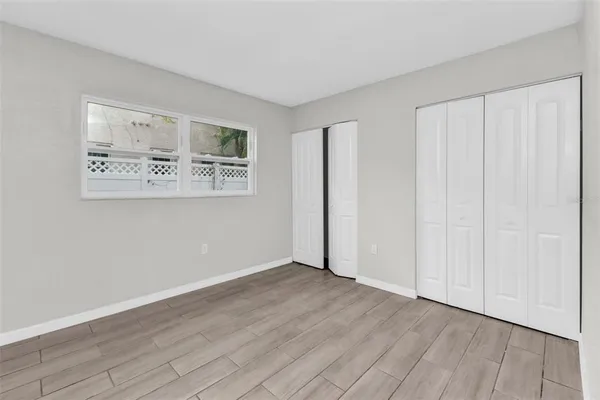 a view of an empty room with window and wooden floor