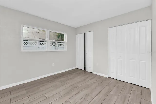 a view of an empty room with window and wooden floor