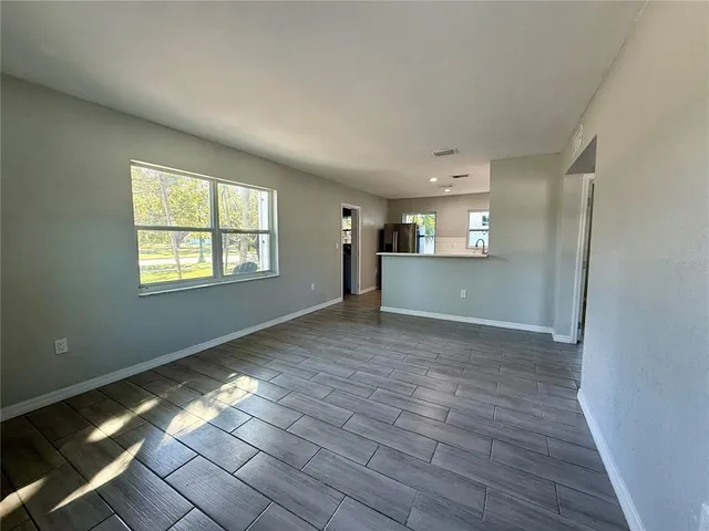 a view of empty room with wooden floor and window