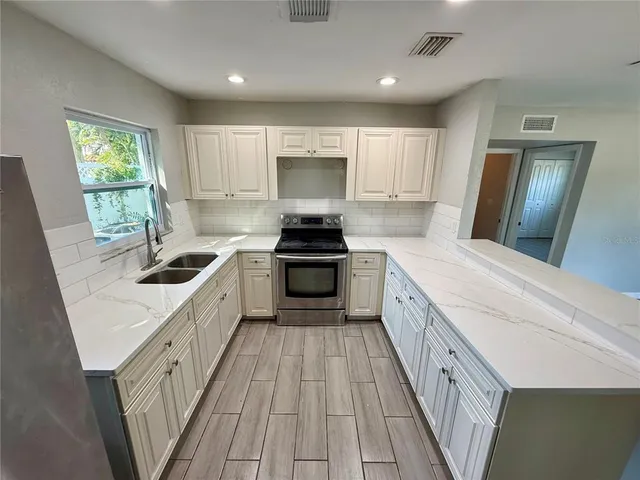 a kitchen with a sink a counter top space cabinets and stainless steel appliances