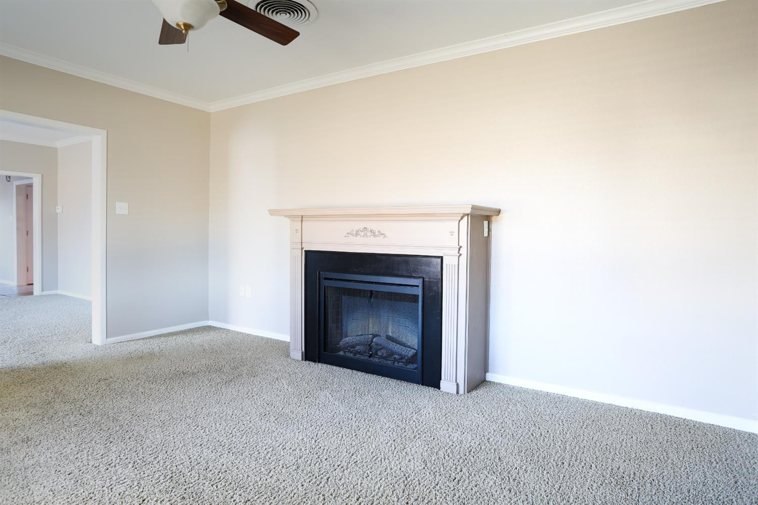 4831 10th Street Lubbock, TX 79416 - Photo 8 of 40 an empty room with a fireplace and fan