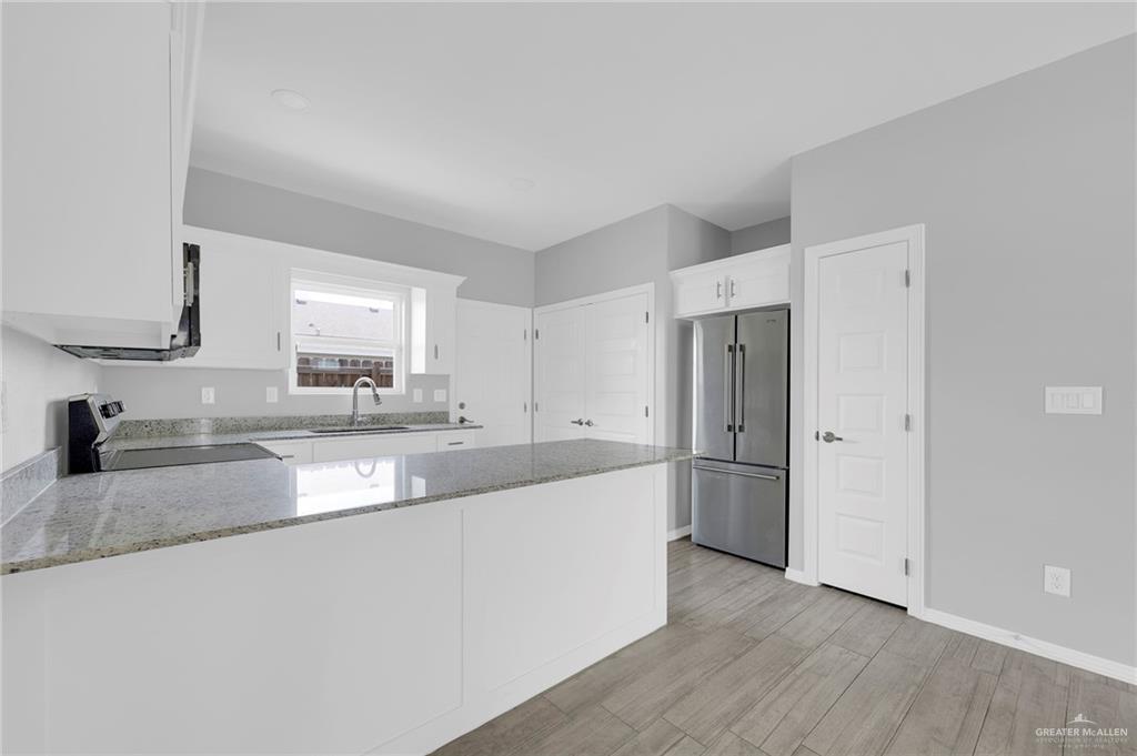 1912 Stauffers Street, Unit 1 Weslaco, TX 78596 - Photo 6 of 14 a large kitchen with a wooden floor and stainless steel appliances