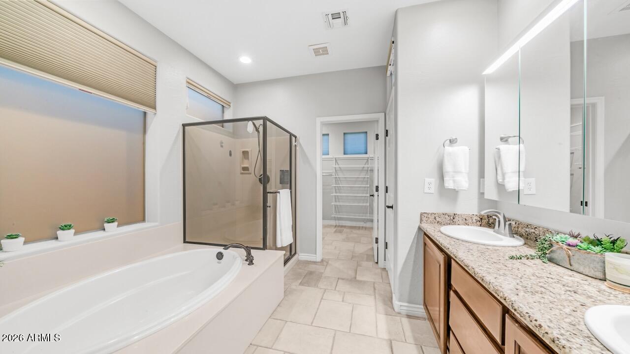 41902 North Crooked Stick Road Anthem, AZ 85086 - Photo 21 of 41 a bathroom with a granite countertop sink a mirror a bathtub and shower