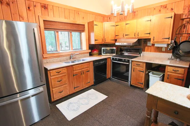 a kitchen with stainless steel appliances granite countertop a refrigerator a stove and a sink