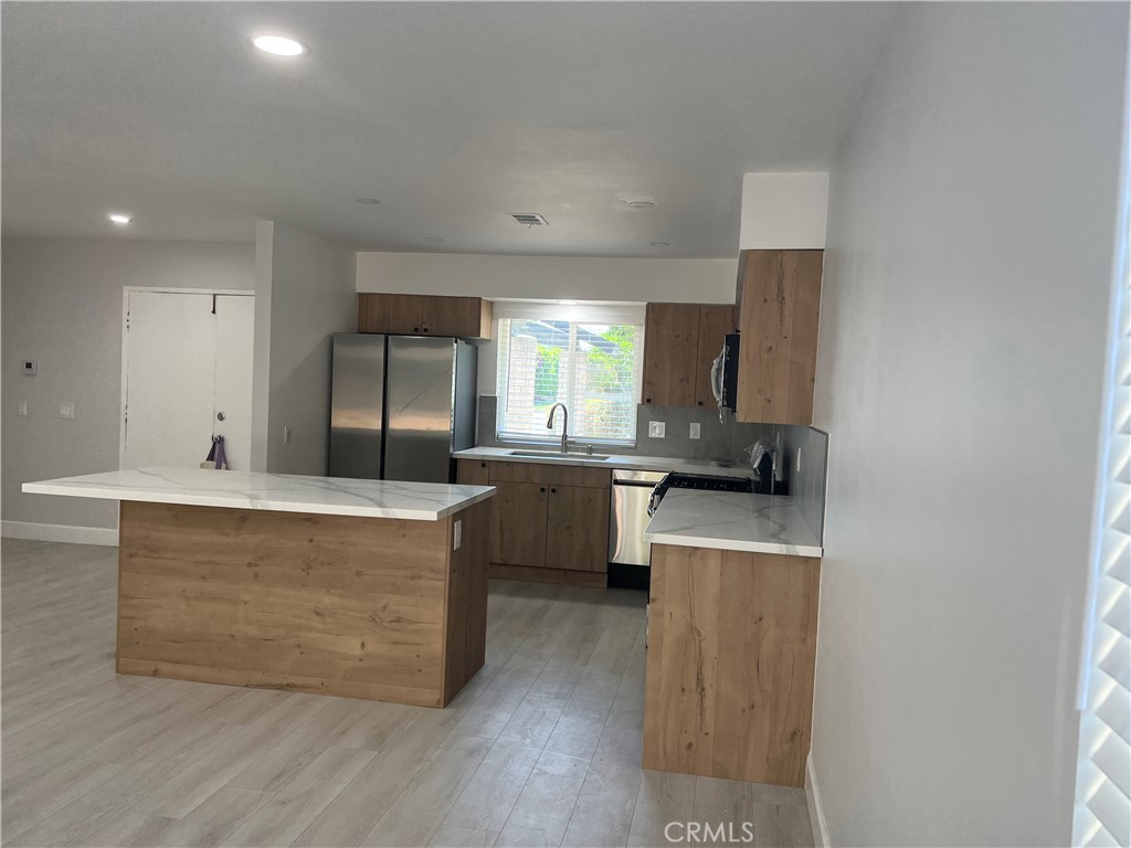 7561 Donna Avenue Reseda, CA 91335 - Photo 4 of 30 a large kitchen with kitchen island a large counter top space a sink stainless steel appliances and cabinets