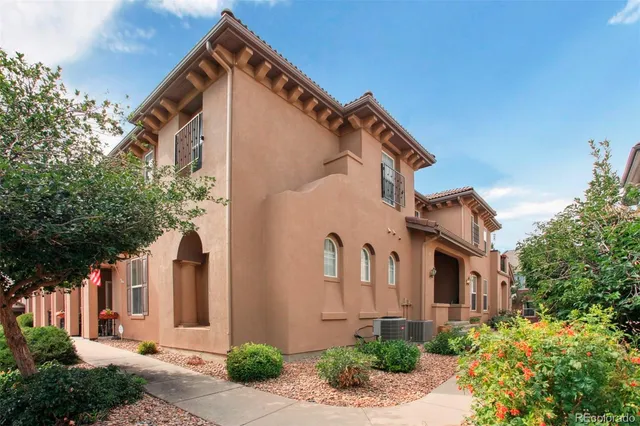 a view of a white house with large windows and flower plants