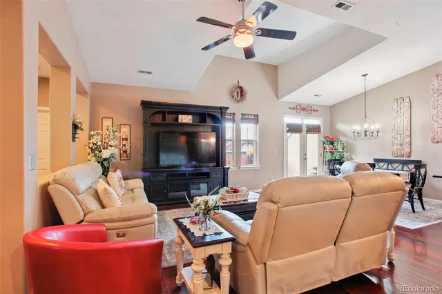 a living room with furniture a ceiling fan and a flat screen tv