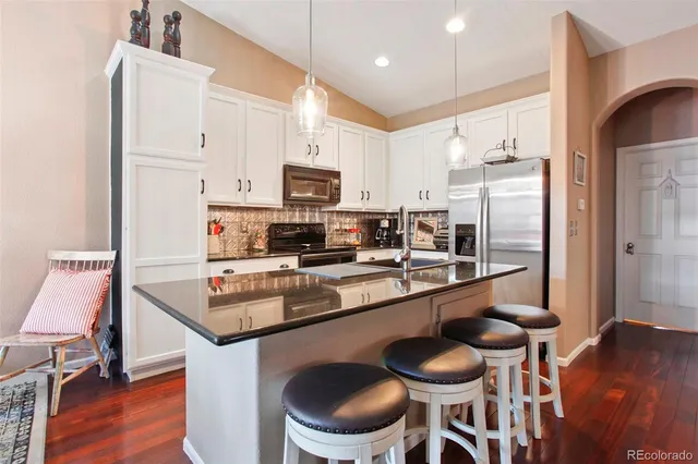 a kitchen with stainless steel appliances a dining table chairs sink and cabinets