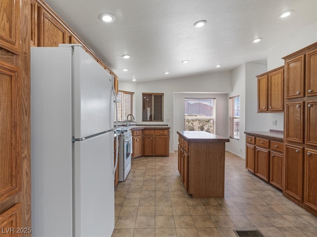 70 West Bonanza Road Las Vegas, NV 89124 - Photo 20 of 71 Kitchen featuring white appliances, a center island, brown cabinetry, recessed lighting, and light tile patterned flooring
