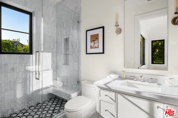 a bathroom with a granite countertop sink toilet a mirror and shower