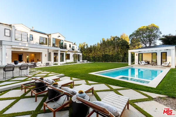 a view of a house with pool lawn chairs and a yard