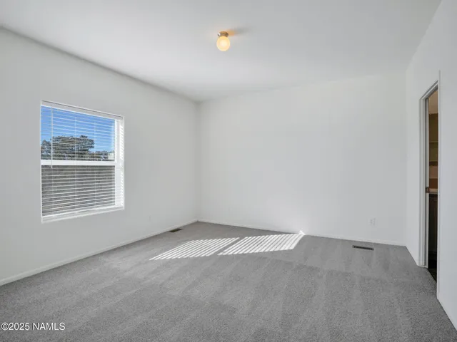 a spacious bedroom with a bed and wooden floor