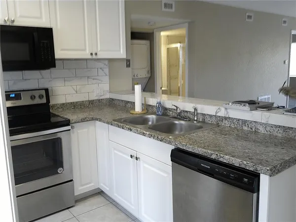 a kitchen with granite countertop a sink dishwasher a stove and a microwave oven on granite countertops