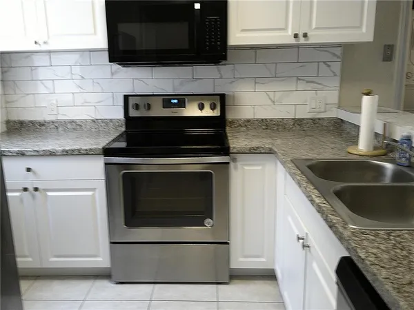 a kitchen with granite countertop a stove sink and cabinets