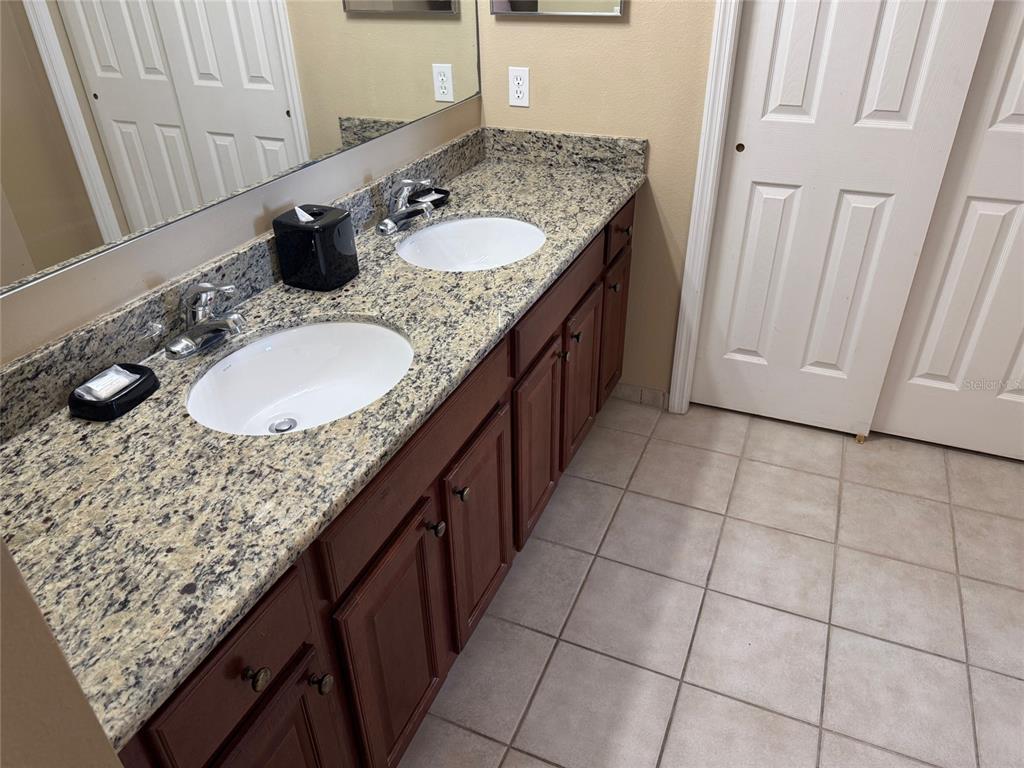 8762 Worldquest Boulevard, Unit 6203 Orlando, FL 32821 - Photo 19 of 31 a bathroom with a granite countertop sink a mirror and vanity