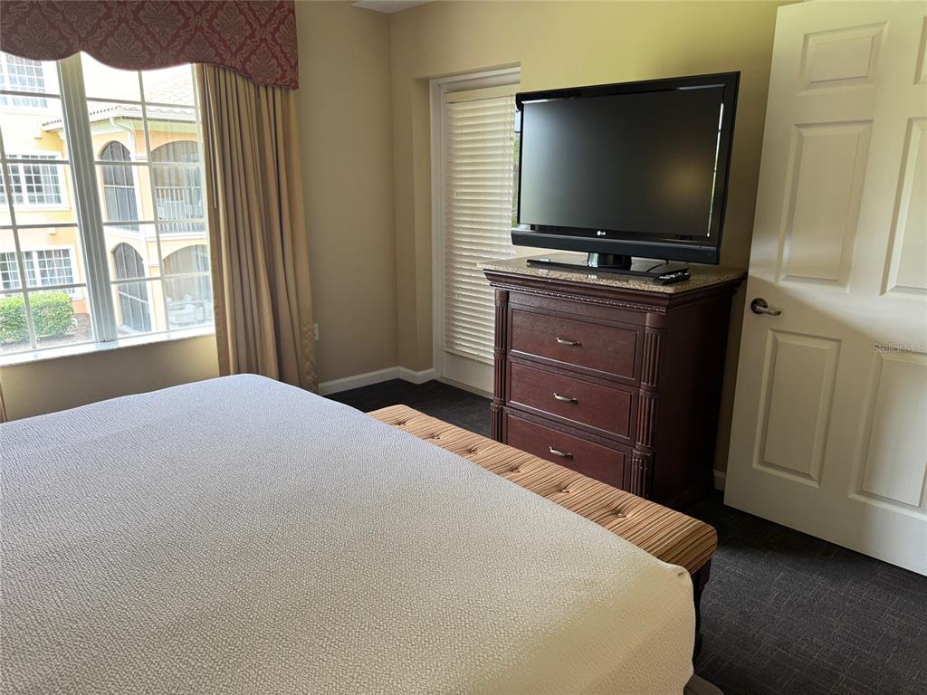 8762 Worldquest Boulevard, Unit 6203 Orlando, FL 32821 - Photo 23 of 31 a bedroom with a bed and a flat screen tv