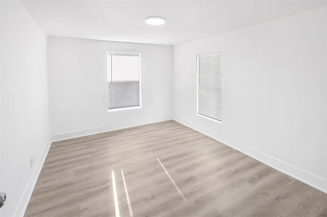 an empty room with wooden floor and windows