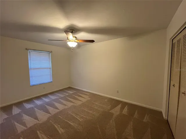 an empty room with windows and fan