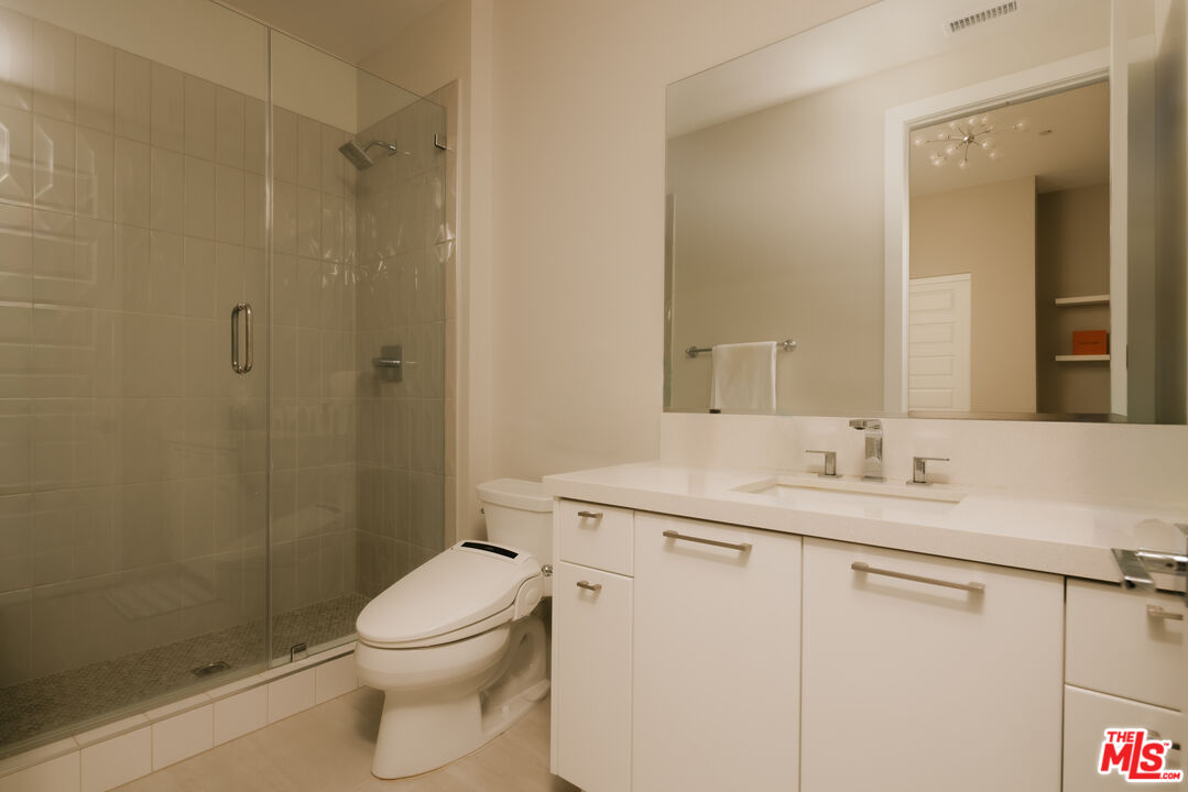 11773 Greenwood Drive Porter Ranch, CA 91326 - Photo 16 of 20 a bathroom with a granite countertop sink toilet a mirror a vanity and shower