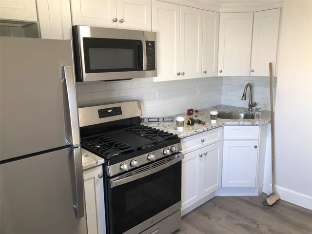 a kitchen with stainless steel appliances white cabinets and stove top oven