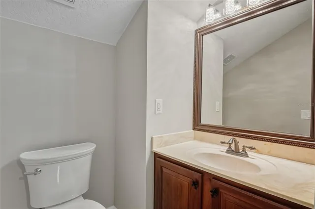 a bathroom with a granite countertop sink a toilet and a mirror