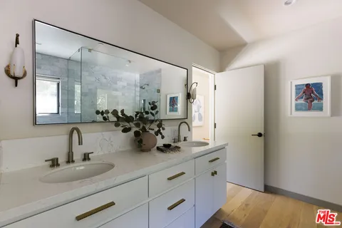 a bathroom with a double vanity sink mirror and shower