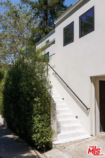 a view of a white house with large windows and a table and chairs