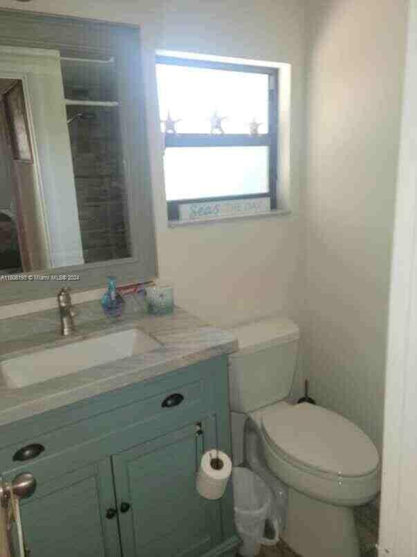 3201 Canal Drive, Unit 2 Pompano Beach, FL 33062 - Photo 10 of 12 a bathroom with a granite countertop toilet a sink and a mirror