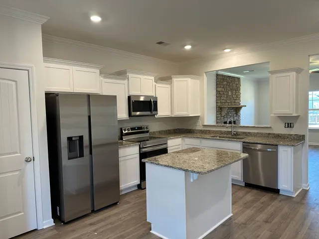 a kitchen with stainless steel appliances granite countertop a refrigerator a stove a sink and a microwave