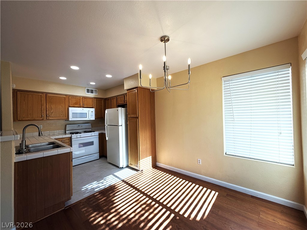 4955 South Lindell Road, Unit 203 Las Vegas, NV 89118 - Photo 3 of 31 A warm kitchen and dining space with natural wood cabinetry and a chandelier.