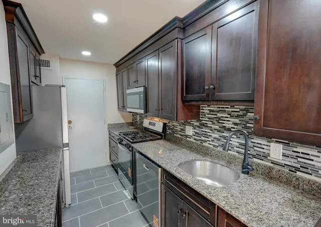 a kitchen with granite countertop stainless steel appliances a sink stove and refrigerator