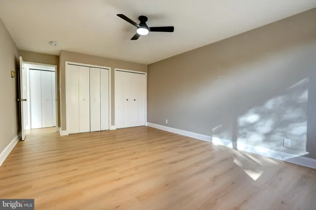 a view of empty room with wooden floor and fan