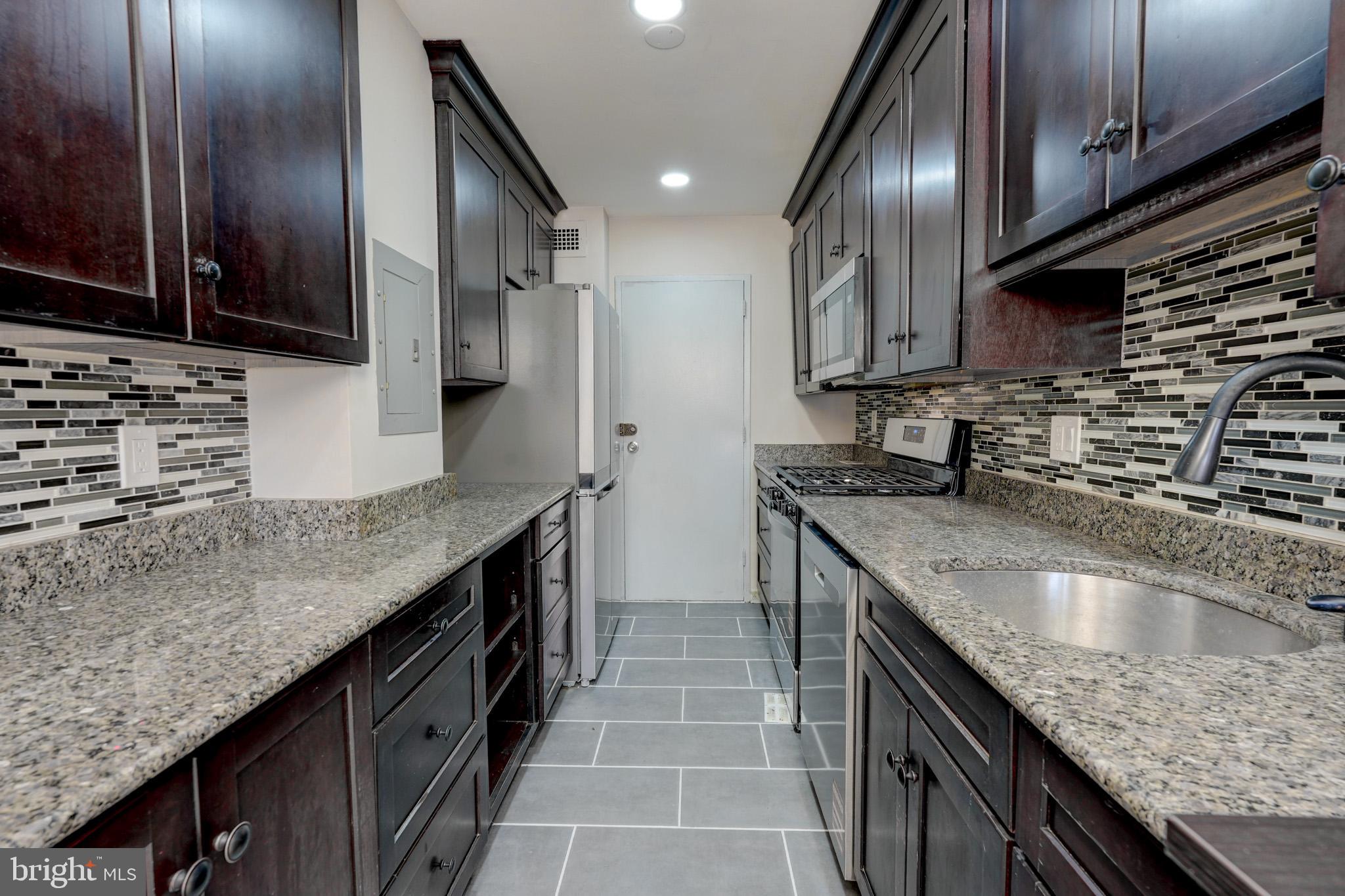 1900 Lyttonsville Road, Unit 211 Silver Spring, MD 20910 - Photo 10 of 46 a kitchen with granite countertop stainless steel appliances and wooden cabinets