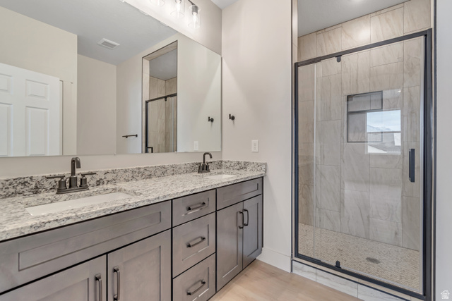 2535 West Santa Fe Drive Mapleton, UT 84664 - Photo 12 of 24 Bathroom featuring a dual vanity with a speckled countertop, undermount sinks, gray shaker-style cabinetry, and dark bronze hardware