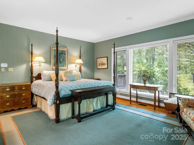 a bedroom with a bed and large windows