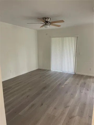 an empty room with wooden floor fan and windows