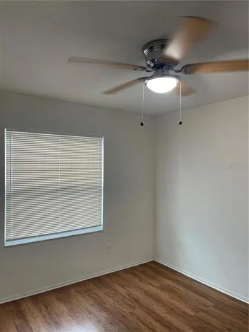 a view of empty room with wooden floor and fan