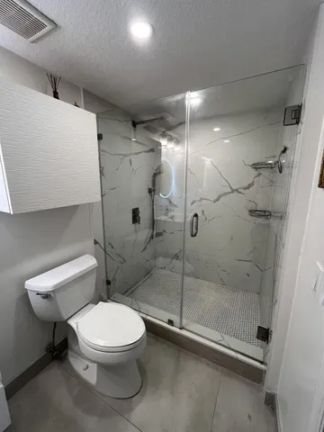 a white toilet sitting next to a shower