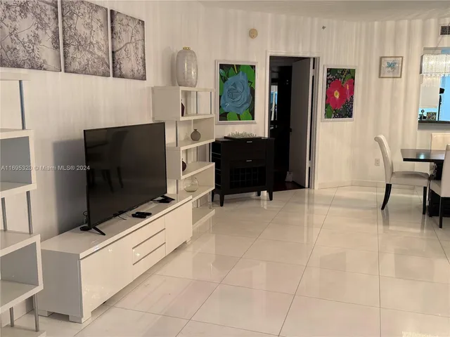 a living room with stainless steel appliances furniture a rug and a refrigerator