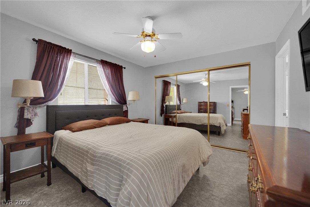 7570 West Flamingo Road, Unit 115 Las Vegas, NV 89147 - Photo 15 of 34 Well-lit sleeping quarters with a ceiling fan, tiled floors, and mirrored closet doors.