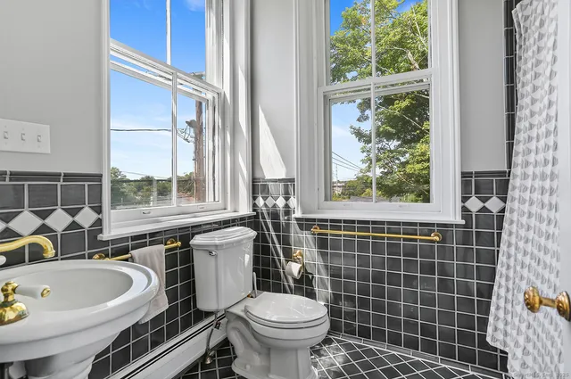 a bathroom with a sink a toilet a mirror and a window