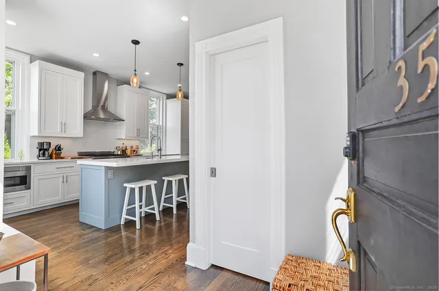 a kitchen with kitchen island granite countertop wooden floors and white cabinets