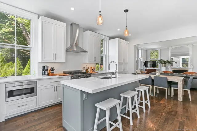 a kitchen with a stove a sink a kitchen island with a dining table and chairs