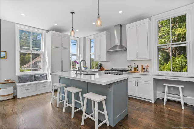 a kitchen with stainless steel appliances granite countertop a stove a sink a oven a dining table and chairs with wooden floor