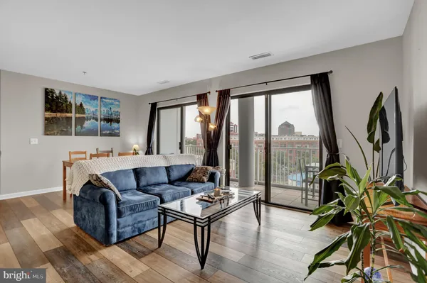 a living room with furniture a large window and wooden floor