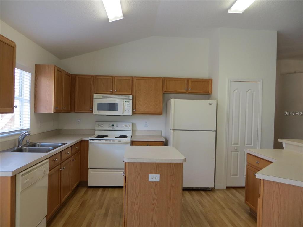 1012 Torreya Way Odessa, FL 33556 - Photo 8 of 40 a kitchen with a refrigerator a stove a sink a microwave a counter space and cabinets