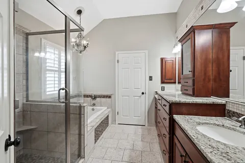 a bathroom with a granite countertop double vanity sink a mirror and a bathtub