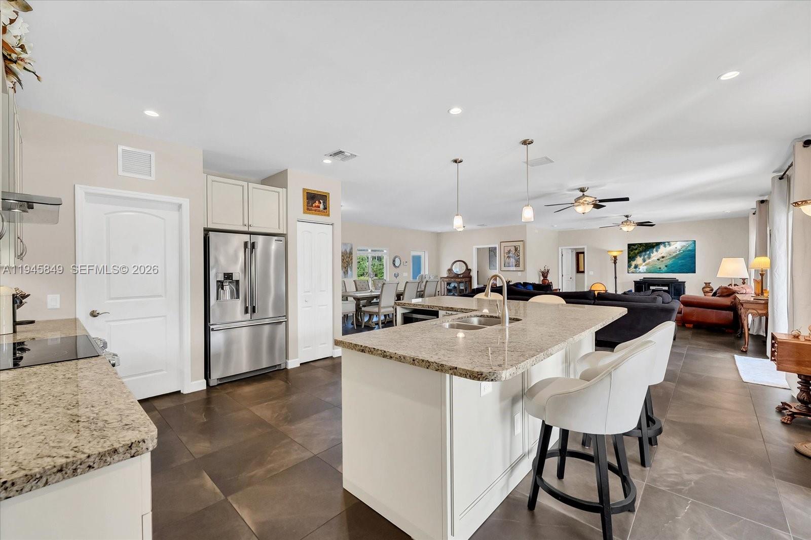 15150 Southwest 240th Street Homestead, FL 33032 - Photo 12 of 38 a open kitchen with stainless steel appliances kitchen island a table chairs and a refrigerator